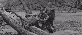 Movie still from “Dersu Uzala” (1975), directed by Akira Kurosawa – Two men are standing next to a tree; Medium shot, High angle