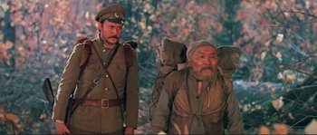 Movie still from “Dersu Uzala” (1975), directed by Akira Kurosawa – A man in a military uniform and a man with a backpack; Medium shot, Low angle