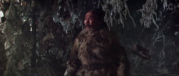 Movie still from “Dersu Uzala” (1975), directed by Akira Kurosawa – An old man in a fur coat is sitting in front of a christmas tree; Medium shot, Low angle