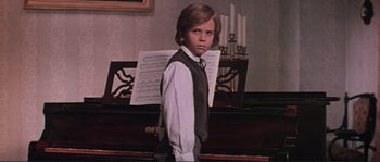 Movie still from “Dersu Uzala” (1975), directed by Akira Kurosawa – A young boy standing in front of a piano; Medium shot, Low angle