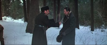 Movie still from “Dersu Uzala” (1975), directed by Akira Kurosawa – Two men in winter coats and hats are standing in the snow; Medium shot, High angle