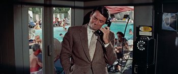 Movie still from “Designing Woman” (1957), directed by Vincente Minnelli – A man talking on a phone while standing in front of a pool; Medium shot, Over the shoulder angle