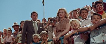 Movie still from “Designing Woman” (1957), directed by Vincente Minnelli – A group of people that are standing in a crowd; Medium shot, Low angle