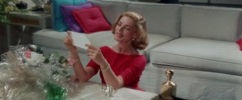 Movie still from “Designing Woman” (1957), directed by Vincente Minnelli – A woman sitting at a table holding a piece of paper; Medium shot, Low angle