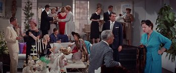 Movie still from “Designing Woman” (1957), directed by Vincente Minnelli – A group of people sitting and standing around a room; Wide shot, High angle