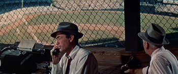 Movie still from “Designing Woman” (1957), directed by Vincente Minnelli – A man wearing a hat talking on a cell phone; Medium shot, High angle