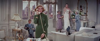Movie still from “Designing Woman” (1957), directed by Vincente Minnelli – A woman talking on a phone in front of other women; Medium shot, Low angle