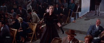 Movie still from “Designing Woman” (1957), directed by Vincente Minnelli – A woman in a black dress is walking down the aisle; Wide shot, Over the shoulder angle