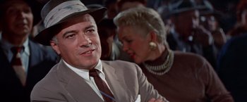 Movie still from “Designing Woman” (1957), directed by Vincente Minnelli – A man in a suit and a woman in a brown suit; Close Up shot, Low angle