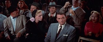 Movie still from “Designing Woman” (1957), directed by Vincente Minnelli – A group of people sitting in a room; Medium shot, Over the shoulder angle