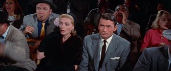 Movie still from “Designing Woman” (1957), directed by Vincente Minnelli – A man and a woman sitting next to each other in front of a crowd; Close Up shot, High angle