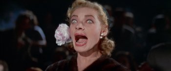 Movie still from “Designing Woman” (1957), directed by Vincente Minnelli – A person with a flower in her mouth; Close Up shot, Low angle