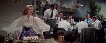 Movie still from “Designing Woman” (1957), directed by Vincente Minnelli – A group of people sitting around a table; Medium shot, Over the shoulder angle