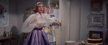 Movie still from “Designing Woman” (1957), directed by Vincente Minnelli – Two women in a kitchen one is holding a pot and the other is holding a plate; Medium shot, Low angle