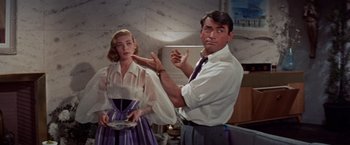 Movie still from “Designing Woman” (1957), directed by Vincente Minnelli – A man and a woman are standing in a room; Medium shot, Over the shoulder angle
