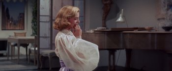 Movie still from “Designing Woman” (1957), directed by Vincente Minnelli – A woman in a white shirt and a purple dress; Medium shot, Over the shoulder angle