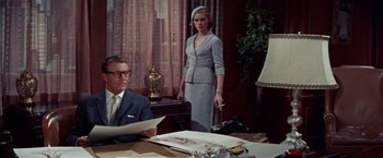 Movie still from “Designing Woman” (1957), directed by Vincente Minnelli – A man and a woman are standing in front of a desk; Medium shot, Low angle