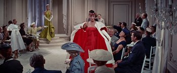 Movie still from “Designing Woman” (1957), directed by Vincente Minnelli – A woman in a red dress and a white coat; Wide shot, Over the shoulder angle