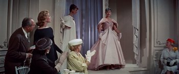 Movie still from “Designing Woman” (1957), directed by Vincente Minnelli – A woman sitting in front of two other women in dresses; Medium shot, Low angle