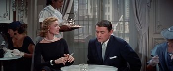 Movie still from “Designing Woman” (1957), directed by Vincente Minnelli – A man and a woman sitting in front of a table; Medium shot, Over the shoulder angle