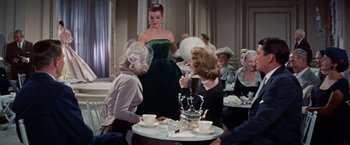 Movie still from “Designing Woman” (1957), directed by Vincente Minnelli – A group of women sitting at a table with cups of tea; Medium shot, Over the shoulder angle