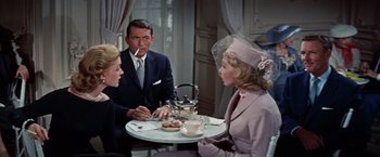 Movie still from “Designing Woman” (1957), directed by Vincente Minnelli – A man and two women sitting at a table; Medium shot, High angle