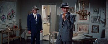 Movie still from “Designing Woman” (1957), directed by Vincente Minnelli – A man in a suit and tie holding a carrot; Medium shot, Low angle