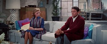 Movie still from “Designing Woman” (1957), directed by Vincente Minnelli – A man and a woman sitting on a couch in a living room; Medium shot, Over the shoulder angle
