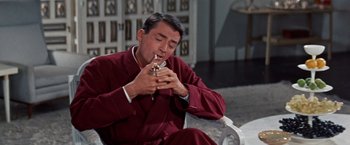 Movie still from “Designing Woman” (1957), directed by Vincente Minnelli – A man sitting on a chair and smoking a cigarette; Medium shot, High angle