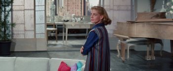 Movie still from “Designing Woman” (1957), directed by Vincente Minnelli – A woman standing in front of a table with clothes on top of it; Medium shot, Over the shoulder angle