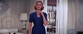 Movie still from “Designing Woman” (1957), directed by Vincente Minnelli – A woman in a blue dress holding a necklace in her hand; Medium shot, Low angle