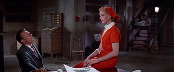 Movie still from “Designing Woman” (1957), directed by Vincente Minnelli – A woman in a red dress sitting on a chair; Medium shot, Low angle