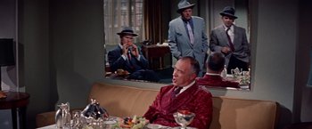 Movie still from “Designing Woman” (1957), directed by Vincente Minnelli – A group of men sitting around a table in front of a mirror; Medium shot, Over the shoulder angle