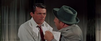 Movie still from “Designing Woman” (1957), directed by Vincente Minnelli – A man in a hat and a tie talking to another man in a hat and a tie; Close Up shot, Over the shoulder angle