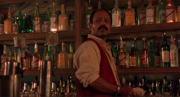Movie still from “Desperado” (1995), directed by Robert Rodriguez – A man standing in front of a wall full of bottles; Medium shot, Low angle