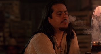 Movie still from “Desperado” (1995), directed by Robert Rodriguez – A man with long black hair is smoking a cigarette; Close Up shot, Low angle