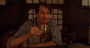 Movie still from “Desperado” (1995), directed by Robert Rodriguez – A man sitting at a table with a cup of coffee; Medium shot, Low angle