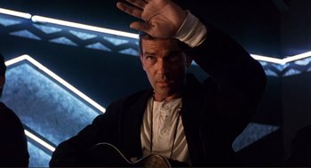 Movie still from “Desperado” (1995), directed by Robert Rodriguez – A man in a white shirt and black jacket holding a guitar; Medium shot, Low angle