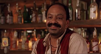 Movie still from “Desperado” (1995), directed by Robert Rodriguez – A man sitting in front of a bunch of liquor bottles; Close Up shot, Low angle