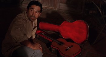 Movie still from “Desperado” (1995), directed by Robert Rodriguez – A man sitting on the ground next to a guitar case; Medium shot, High angle