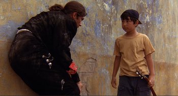 Movie still from “Desperado” (1995), directed by Robert Rodriguez – A man and a boy standing next to each other on the street; Medium shot, Over the shoulder angle