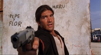 Movie still from “Desperado” (1995), directed by Robert Rodriguez – A man holding a gun in front of a wall; Close Up shot, Low angle