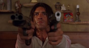 Movie still from “Desperado” (1995), directed by Robert Rodriguez – A person holding guns in a room; Close Up shot, Low angle