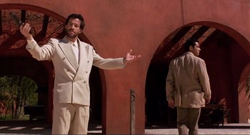 Movie still from “Desperado” (1995), directed by Robert Rodriguez – A man in a white suit standing next to another man in a tan suit; Medium shot, Over the shoulder angle