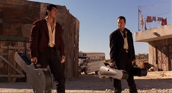 Movie still from “Desperado” (1995), directed by Robert Rodriguez – Two men standing next to each other on a dirt road; Medium shot, Low angle