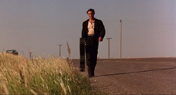 Movie still from “Desperado” (1995), directed by Robert Rodriguez – A man walking down a road holding a skateboard; Wide shot, Low angle