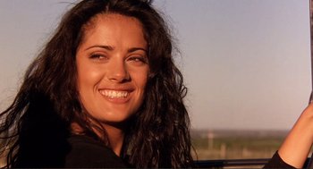 Movie still from “Desperado” (1995), directed by Robert Rodriguez – A person with long black hair smiling; Close Up shot, Low angle
