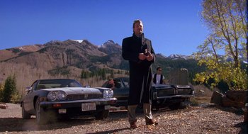 Movie still from “Desperate Hours” (1990), directed by Michael Cimino – A man standing in front of a row of parked cars; Wide shot, Low angle