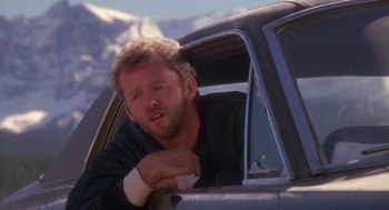 Movie still from “Desperate Hours” (1990), directed by Michael Cimino – A man sitting in the driver's seat of a car with mountains in the background; Close Up shot, Over the shoulder angle