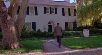 Movie still from “Desperate Hours” (1990), directed by Michael Cimino – A man walking down a sidewalk in front of a house; Extreme Wide shot, Low angle